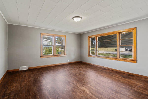 empty room featuring dark wood-type flooring and crown molding