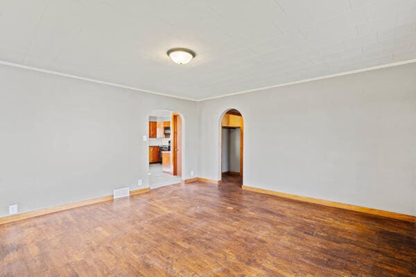 spare room featuring wood-type flooring and crown molding