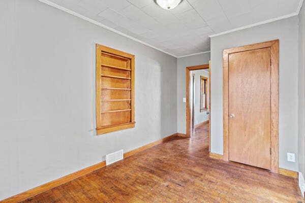 201 N Evans St, Armstrong, MO 65230 - empty room with ornamental molding, wood finished floors, baseboards, and built in shelves
