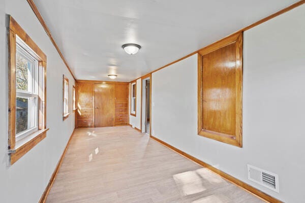 hall featuring ornamental molding and light hardwood / wood-style flooring