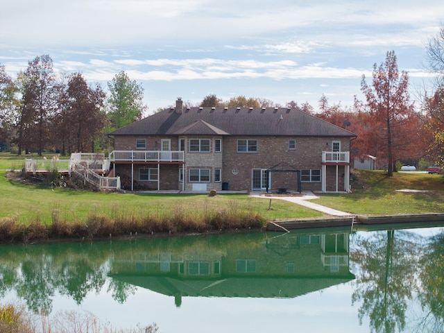 back of property featuring a water view, a yard, and a balcony