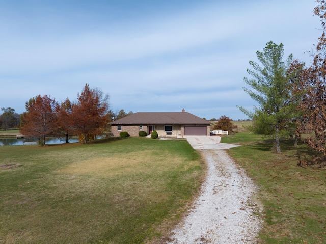 single story home with a garage, a water view, and a front lawn