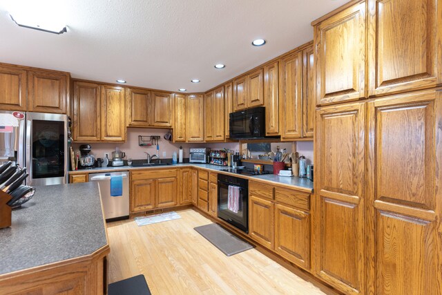 kitchen with sink, black appliances, and light hardwood / wood-style flooring