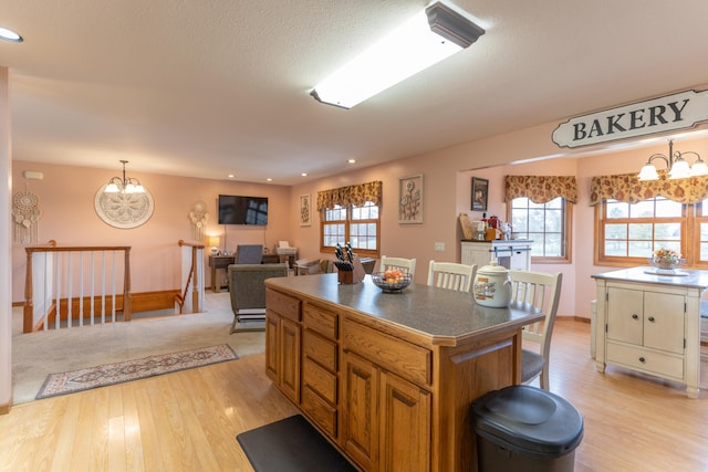 kitchen featuring a kitchen island, decorative light fixtures, a notable chandelier, and light hardwood / wood-style floors