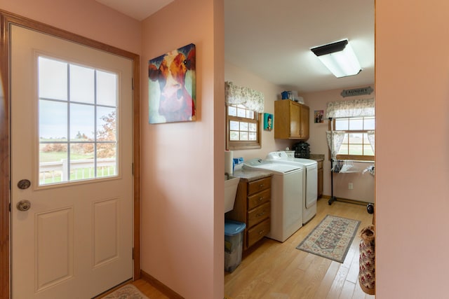 washroom with cabinets, a wealth of natural light, light wood-type flooring, and independent washer and dryer