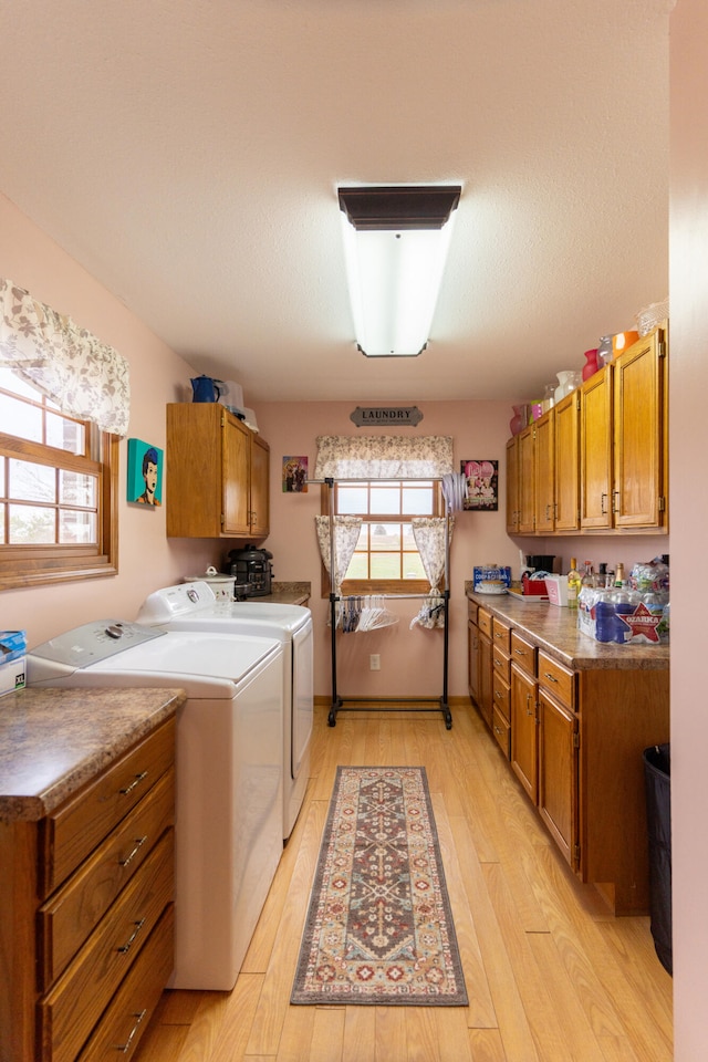 clothes washing area with cabinets, a wealth of natural light, separate washer and dryer, and light wood-type flooring