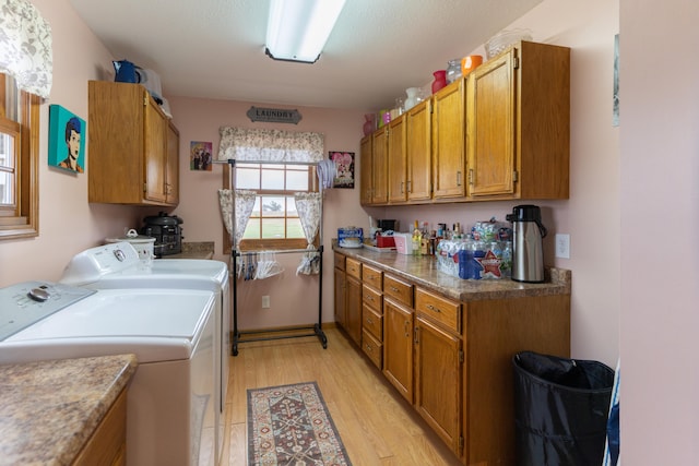 washroom with cabinets, washing machine and clothes dryer, and light hardwood / wood-style floors