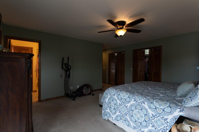 carpeted bedroom featuring ceiling fan and two closets