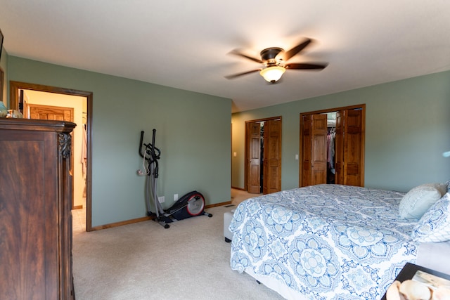 bedroom with ceiling fan, multiple closets, and light colored carpet