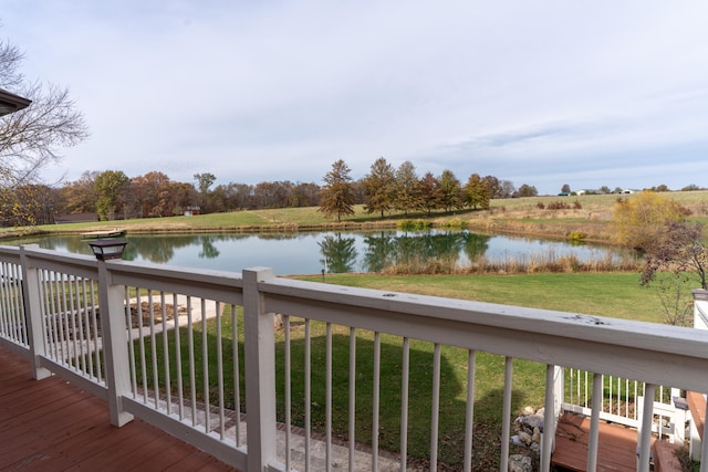 wooden terrace with a water view and a yard