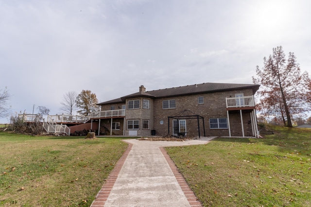 rear view of property featuring a wooden deck and a lawn