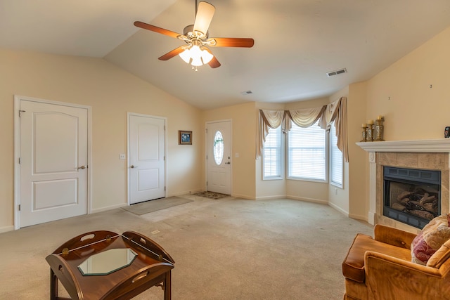 carpeted living room with ceiling fan, a tiled fireplace, and vaulted ceiling