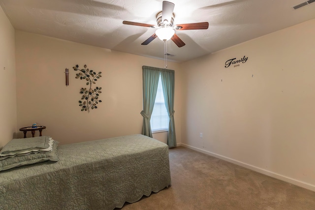 bedroom with ceiling fan, carpet floors, and a textured ceiling