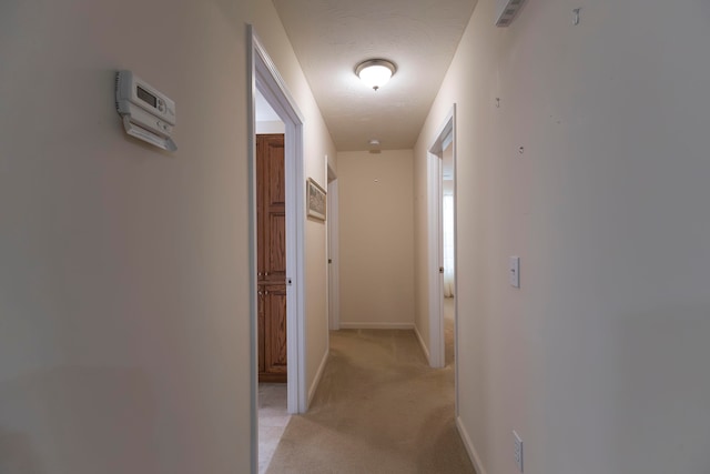 corridor featuring a textured ceiling and light colored carpet