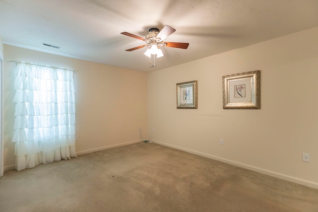 carpeted spare room featuring ceiling fan and a textured ceiling