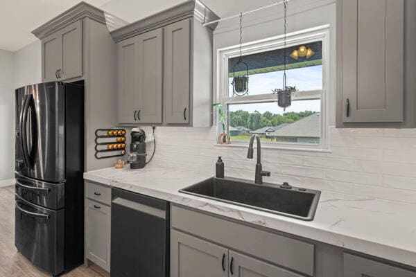 kitchen with backsplash, sink, light stone countertops, and stainless steel appliances