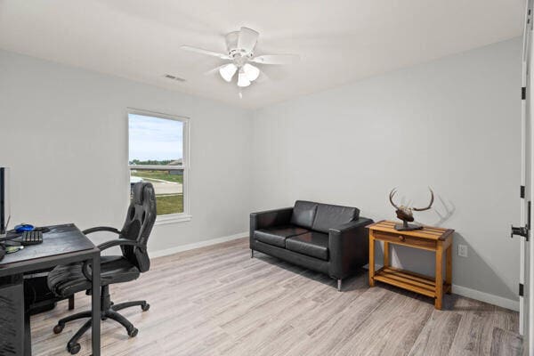 home office with light hardwood / wood-style floors and ceiling fan