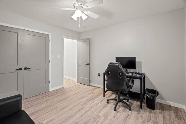 office with light wood-type flooring and ceiling fan