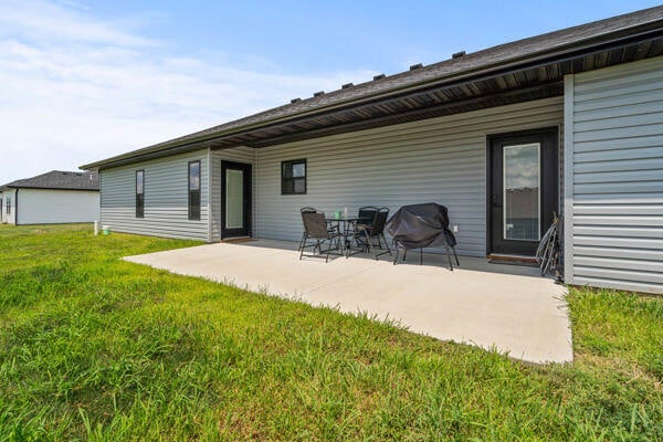 rear view of house featuring a lawn and a patio area