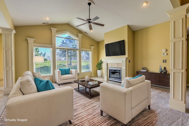 carpeted living room with decorative columns, ceiling fan, lofted ceiling, and a tiled fireplace