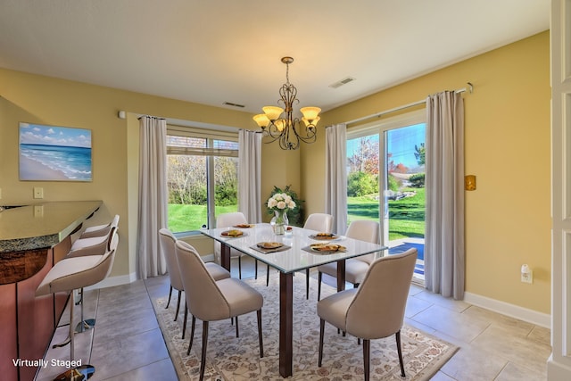 tiled dining room featuring a wealth of natural light and an inviting chandelier