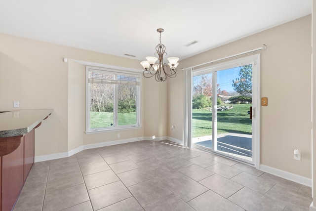 unfurnished dining area with light tile patterned floors, a healthy amount of sunlight, and an inviting chandelier