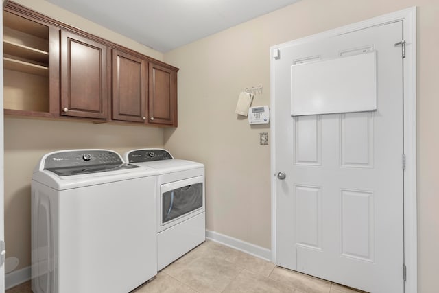 clothes washing area with cabinets, washing machine and dryer, and light tile patterned flooring