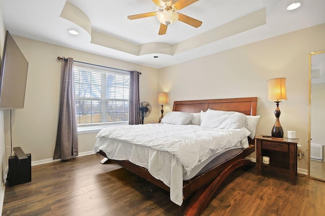 bedroom featuring dark hardwood / wood-style flooring, a raised ceiling, and ceiling fan