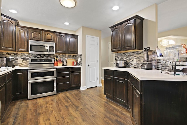 kitchen featuring dark wood-type flooring, dark brown cabinetry, appliances with stainless steel finishes, and tasteful backsplash