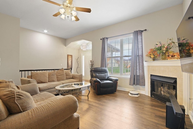 living room featuring a tiled fireplace, hardwood / wood-style floors, and ceiling fan