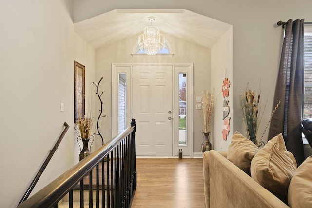 foyer with an inviting chandelier, lofted ceiling, and light hardwood / wood-style flooring