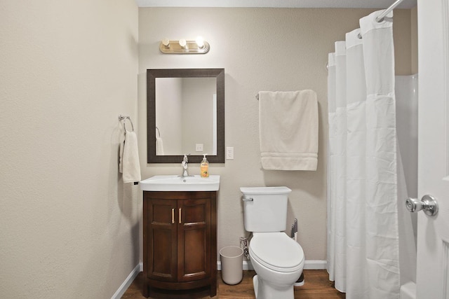 bathroom with hardwood / wood-style flooring, vanity, toilet, and walk in shower