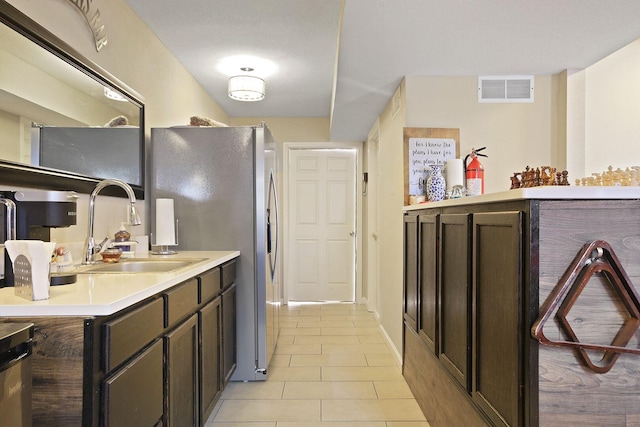 kitchen with sink, dark brown cabinets, stainless steel refrigerator with ice dispenser, and light tile patterned flooring