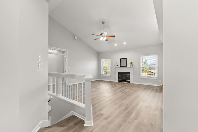 unfurnished living room with ceiling fan, light wood-type flooring, and high vaulted ceiling