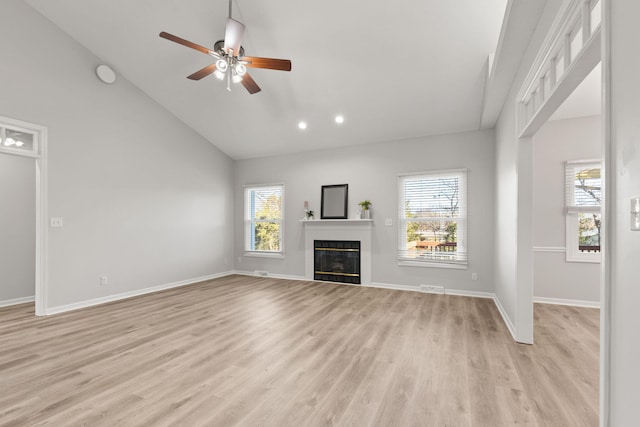 unfurnished living room featuring ceiling fan, light hardwood / wood-style flooring, high vaulted ceiling, and a healthy amount of sunlight