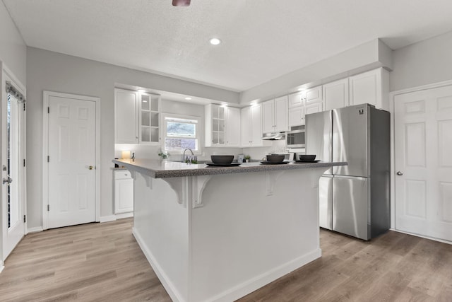 kitchen featuring a kitchen bar, white cabinetry, light hardwood / wood-style flooring, and appliances with stainless steel finishes