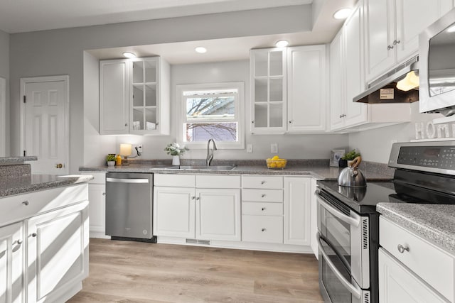 kitchen featuring white cabinetry, sink, dark stone countertops, appliances with stainless steel finishes, and light wood-type flooring