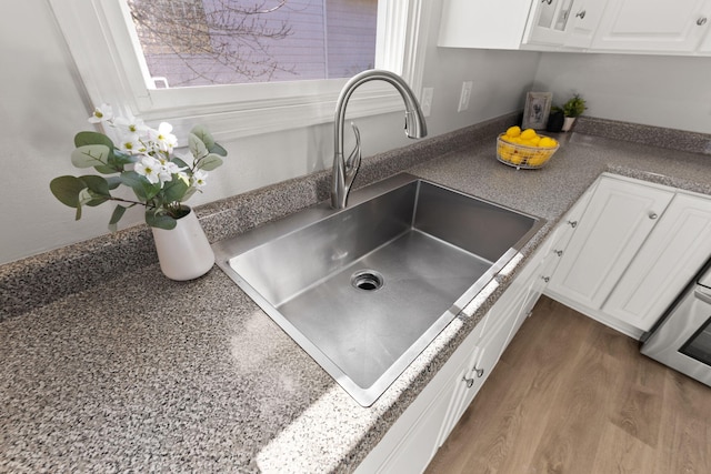 interior details with sink, white cabinets, and dark wood-type flooring