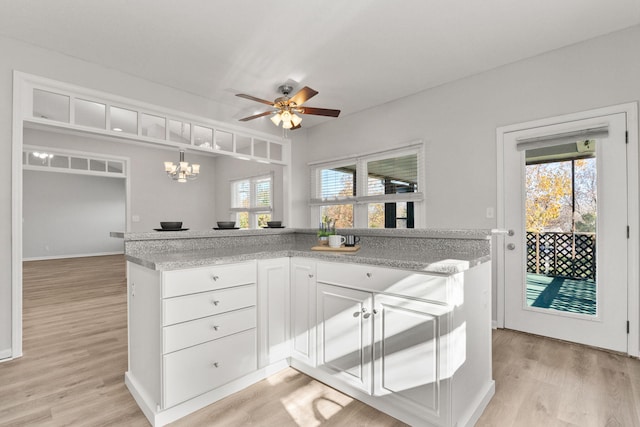 kitchen with white cabinets, light hardwood / wood-style floors, hanging light fixtures, and a wealth of natural light