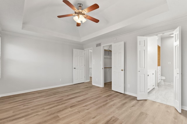 unfurnished bedroom with ceiling fan, light hardwood / wood-style floors, and a tray ceiling