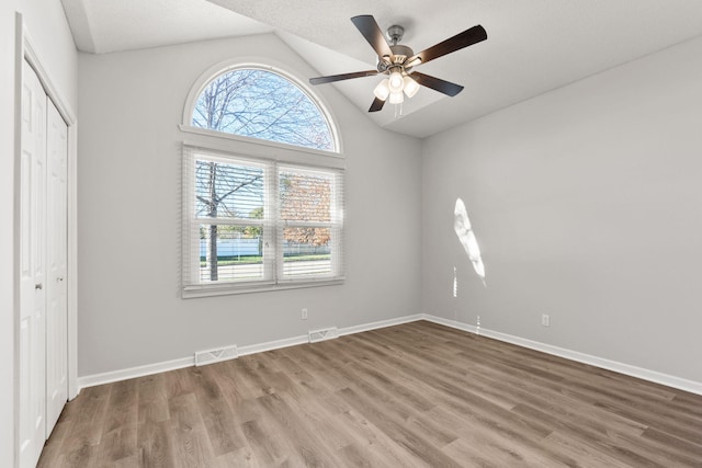 unfurnished bedroom featuring a textured ceiling, vaulted ceiling, ceiling fan, hardwood / wood-style flooring, and a closet