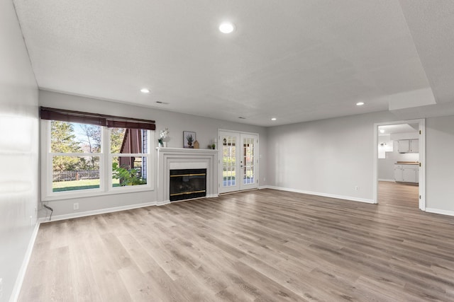 unfurnished living room featuring a textured ceiling, light hardwood / wood-style flooring, and plenty of natural light