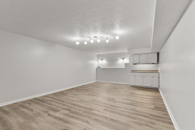 unfurnished living room featuring a textured ceiling and light hardwood / wood-style floors