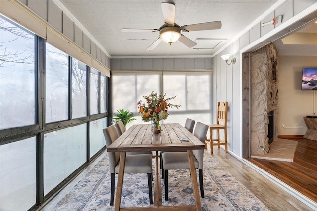 sunroom featuring a stone fireplace and ceiling fan