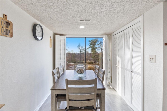 dining area with light wood-type flooring and a textured ceiling