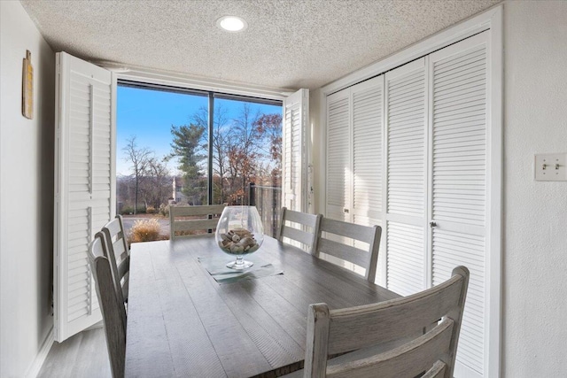 dining space with hardwood / wood-style floors and a textured ceiling