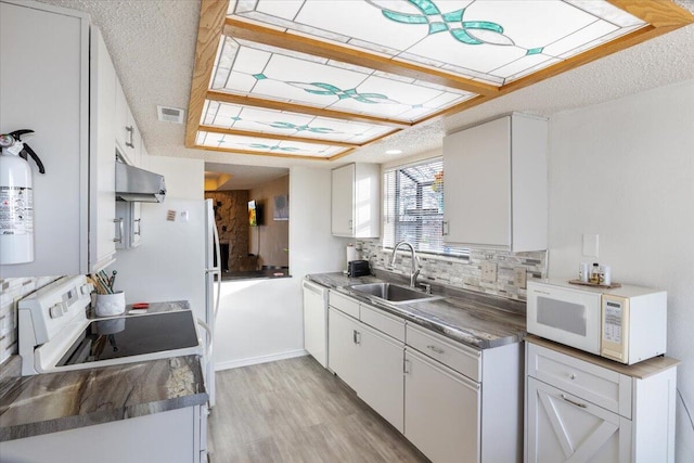 kitchen with decorative backsplash, white appliances, ventilation hood, sink, and white cabinetry