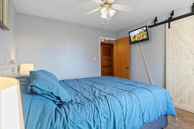 carpeted bedroom featuring a textured ceiling, a barn door, and ceiling fan