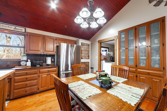 dining room with light wood-type flooring, vaulted ceiling, an inviting chandelier, and wooden ceiling