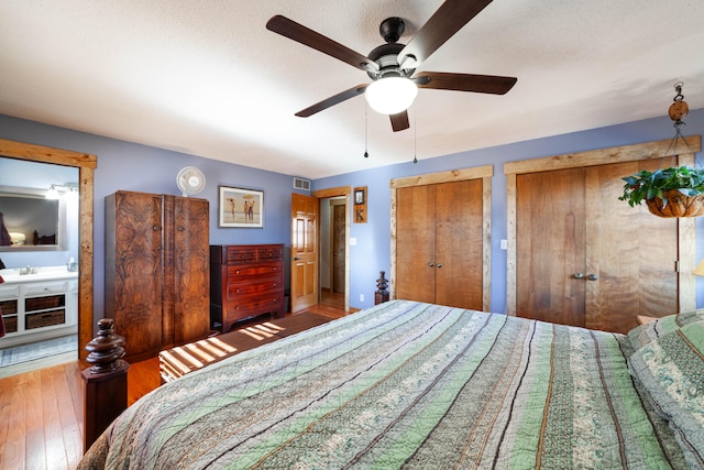 bedroom featuring ceiling fan, hardwood / wood-style flooring, and multiple closets